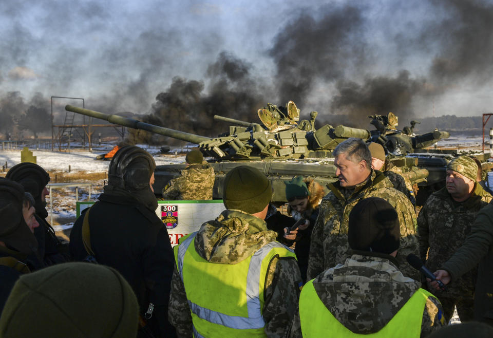 FILE - Ukrainian President Petro Poroshenko, second from right, speak with soldiers during a military training at a military base in Chernihiv region, Ukraine, Nov, 28, 2018. A peace agreement for eastern Ukraine has remained stalled for years, but it has come into the spotlight again amid a Russian military buildup near Ukraine that has fueled invasion fears. On Thursday, Feb. 10, 2022 presidential advisers from Russia, Ukraine, France and Germany are set to meet in Berlin to discuss ways of implementing the deal that was signed in the Belarusian capital of Minsk in 2015. (Mykola Lazarenko/Presidential Press Service via AP, File)