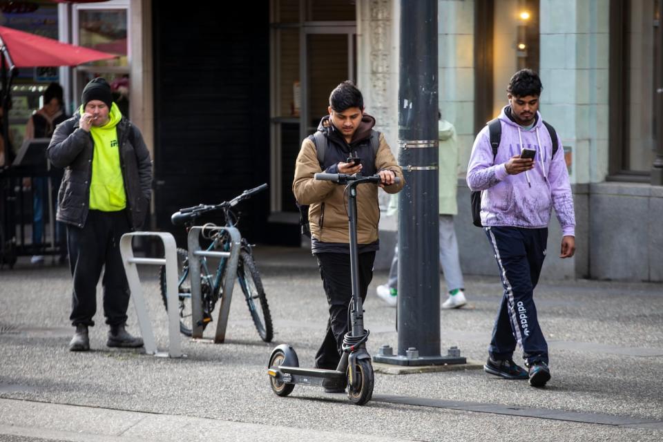 A person rides an electric kick scooter in Vancouver, British Columbia on Thursday, February 22, 2023. 