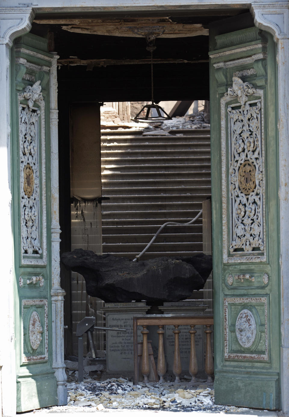 A meteorite on exhibit at the National Museum is seen through a door after an overnight fire in Rio de Janeiro, Brazil, Monday, Sept. 3, 2018. The esteemed museum houses artifacts from Egypt, Greco-Roman art and some of the first fossils found in Brazil. (AP Photo/Silvia Izquierdo)