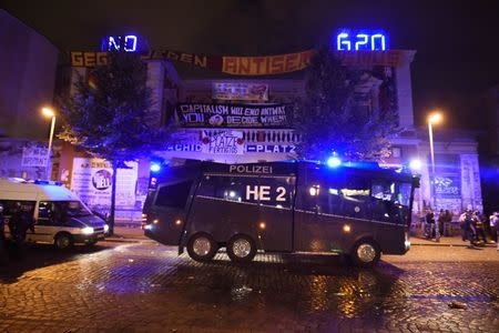 German police cars stay at the front of the protester's placards on the building during the demonstration during the G20 summit in Hamburg, Germany, July 6, 2017. REUTERS/Fabian Bimmer