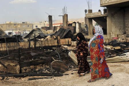 Women walks near the remains of tents that were burnt in a refugee camp for Syrian refugees in Lebanon's Bekaa Valley June 1, 2015. REUTERS/Hassan Abdallah