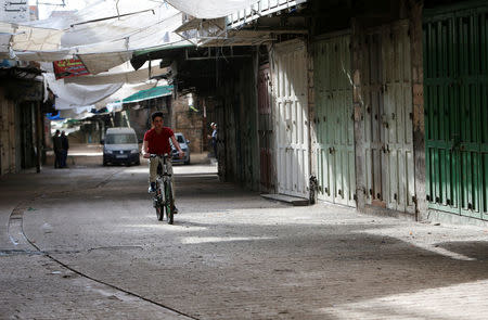 A man passes closed shops as Palestinians call for a general strike, in Hebron, in the occupied West Bank March 31, 2018. REUTERS/Mussa Qawasma