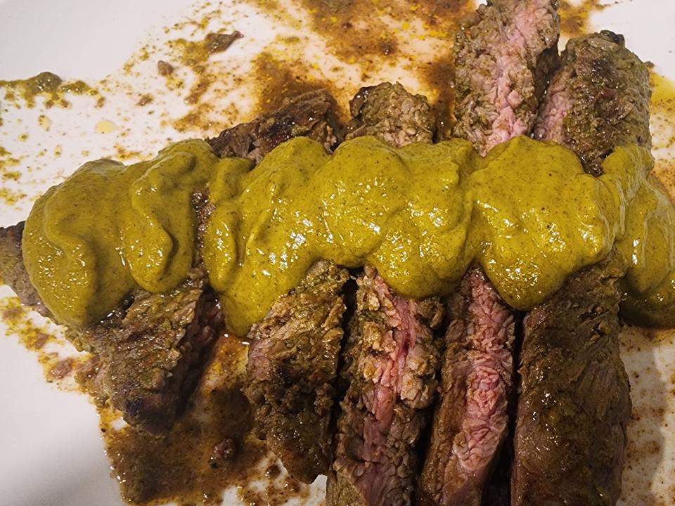 Grilled sliced steak with green marinade on top
