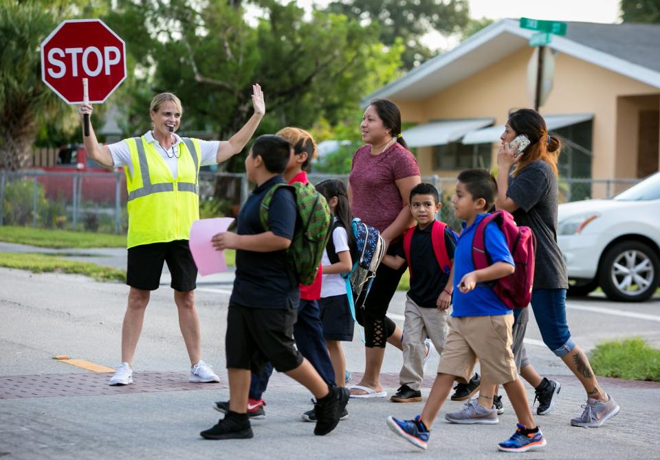 Jupiter Elementary students are assisted by a crossing guard during the first day of classes in 2019.