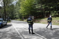 Police officers patrol the road leading to the Stresa-Mottarone cable line for rescue operations to take place after a cable car of the line collapsed, near Stresa, Italy, Sunday, May 23, 2021. A cable car taking visitors to a mountaintop view of some of northern Italy's most picturesque lakes plummeted to the ground Sunday and then tumbled down the slope, killing at least 13 people and sending two children to the hospital, authorities said. (AP Photo/Antonio Calanni)