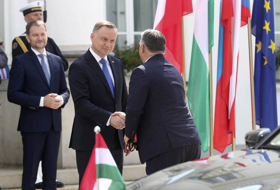 Poland's President Andrzej Duda, center, are welcomes Hungary Prime Minister Viktor Orban, right, for a Visegrad Group summit in Warsaw, Poland, on Friday, July 3, 2020, as Poland takes the rotating presidency of the regional cooperation group that also includes the Czech Republic and Hungary.(AP Photo/Czarek Sokolowski)