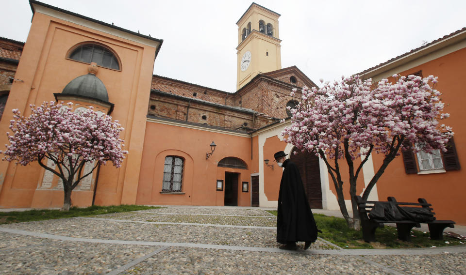 In this photo taken on Thursday, March 12, 2020, a priest wearing a mask walks in Codogno, Italy. The northern Italian town that recorded Italy’s first coronavirus infection has offered a virtuous example to fellow Italians, now facing an unprecedented nationwide lockdown, that by staying home, trends can reverse. Infections of the new virus have not stopped in Codogno, which still has registered the most of any of the 10 Lombardy towns Italy’s original red zone, but they have slowed. For most people, the new coronavirus causes only mild or moderate symptoms. For some it can cause more severe illness. (AP Photo/Antonio Calanni)