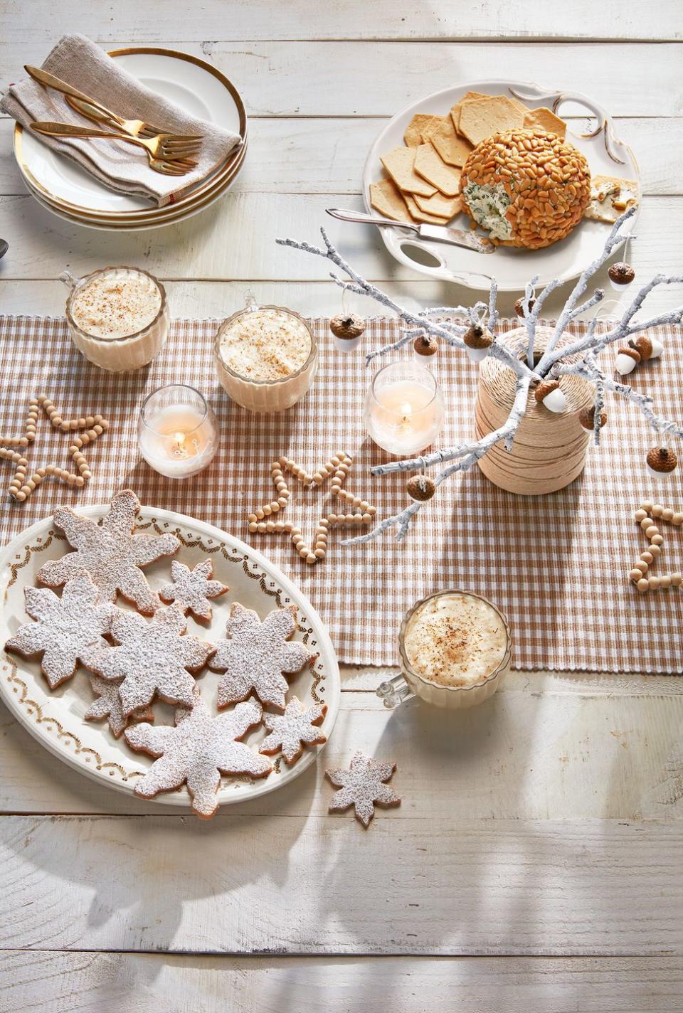 <p>This tablescape is full of Christmas craft ideas. First, create a winter "bouquet" like this one using found branches, a spool of beige thread, and white paint. Then use pipe cleaners and small wooden beads to create star decor. </p>