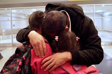 Fadi Kassar (L) hugs his daughters Hnan, 8 and Lian, 5, for the first time in more than 2 years with his wife Razan (not pictured) looks on after the family was reunited following a flight from Amman, Jordan, at John F. Kennedy International airport in New York City February 2, 2017. Bill Swersey/HIAS.org/Handout via REUTERS