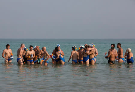 Environmental activists cheer each other as they finish "The Dead Sea Swim Challenge", swimming from the Jordanian to Israeli shore, to draw attention to the ecological threats facing the Dead Sea, in Kibbutz Ein Gedi, Israel November 15, 2016. REUTERS/Nir Elias