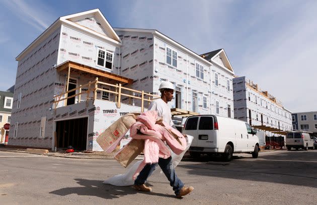 A worker carries insulation at a new housing construction site in Alexandria, Virginia, in 2012. Two programs in the Inflation Reduction Act will offer federal tax rebates to subsidize home improvement projects that save energy or swap appliances to electric alternatives.