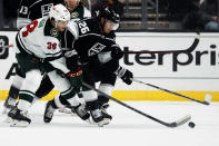 Minnesota Wild forward Ryan Hartman (38) and Los Angeles Kings defenseman Sean Walker (26) reach for the puck during the first period of an NHL hockey game Saturday, Oct. 16, 2021, in Los Angeles. (AP Photo/Ringo H.W. Chiu)