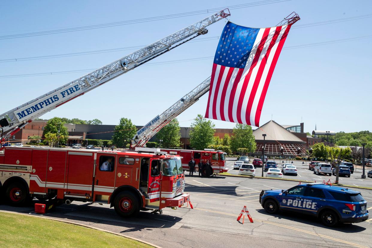 A Memphis Police Department officer drives past an American flag displayed between two Memphis Fire Department trucks outside of Hope Church prior to the start of the funeral for Joseph McKinney, a Memphis Police Department officer who was killed during a shootout on April 12, in Cordova, Tenn., on Monday, April 22, 2024.