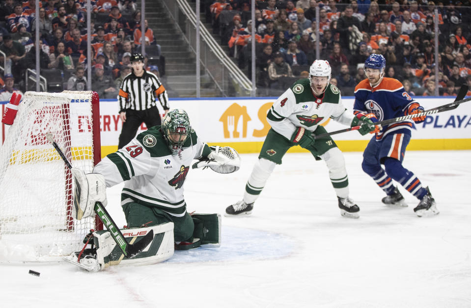 Minnesota Wild goalie Marc-Andre Fleury (29) makes a save as Jon Merrill (4) and Edmonton Oilers' Warren Foegele (37) look for the rebound during the second period of an NHL hockey game Friday, Dec. 8, 2023, in Edmonton, Alberta. (Jason Franson/The Canadian Press via AP)