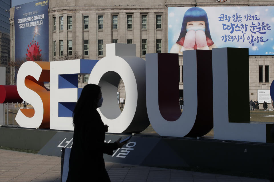 A woman wearing a face mask as a precaution against the coronavirus walks near the display of South Korea's capital Seoul logo in Seoul, South Korea, Monday, Dec. 21, 2020. (AP Photo/Lee Jin-man)