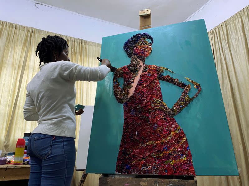Marcellina Akpojotor creates an art piece of a woman with a face mask using waste Ankara fabric in Lagos