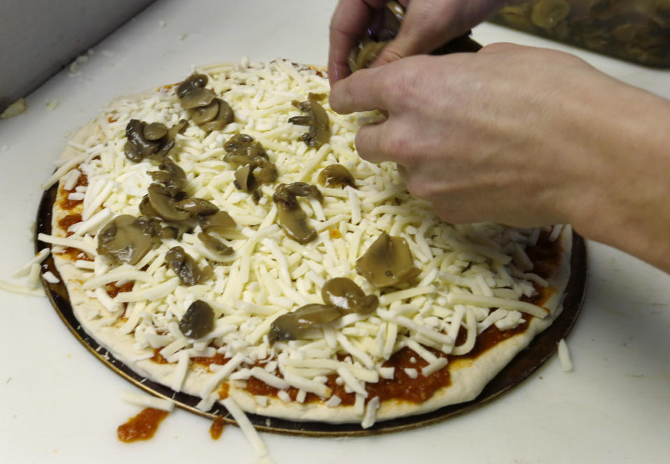 In this photo made on Saturday, March 1, 2014, Brian Scritchfield adds mushrooms to a small pizza ordered at Bobtown Pizza in Bobtown, Pa. The little pizza shop in the southwestern corner of Pennsylvania was placed in the spotlight when energy giant Chevron offered coupons for free pizza from their shop to people who live near the area where a natural gas well that exploded, killing one worker on Feb 11, 2014. Some news stories and internet opinion posts have been critical about the offer by Chevron Corp., but many residents of the town said they didn’t mind the pizza offer. (AP Photo/Keith Srakocic)