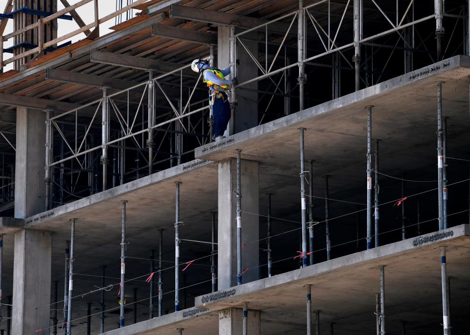 A worker tethered to the building looks up as his crew prepares to lift a concrete from out of the under-construction DoubleTree by Hilton hotel in downtown Abilene on Tuesday. Tourism in Abilene rebounded in 2021 as the city emerged from a pandemic that stalled the industry statewide.