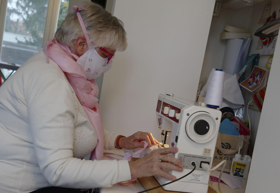 In this photo taken on Thursday, March 19, 2020, Magda Leonard, sews a face mask, meant to help protect from the spread of COVID-19, at her home in Edegem, Belgium. Leonard is making masks for family and friends, along with her daughter, and hopes to be able to produce enough to deliver to caregivers and local doctors. Belgium currently has a need for the masks due to a shortage in supply of industrially made masks. For most people, the new coronavirus causes only mild or moderate symptoms, such as fever and cough. For some, especially older adults and people with existing health problems, it can cause more severe illness, including pneumonia. (Gerd Moyson via AP)
