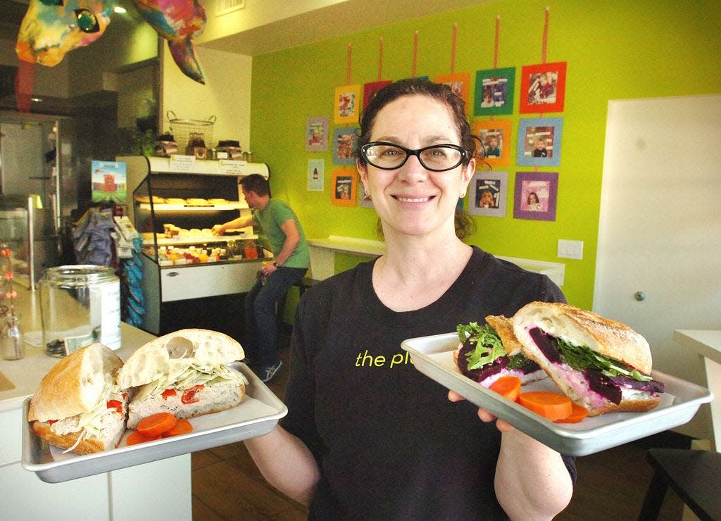 Suzanne Lombardi, owner of The Plate, shows off a Sicilian Tuna Sandwich and Roasted Beet sandwich with arugula at her original Milton Village location in 2013. Lombardi opened a second location in East Milton Square this year.