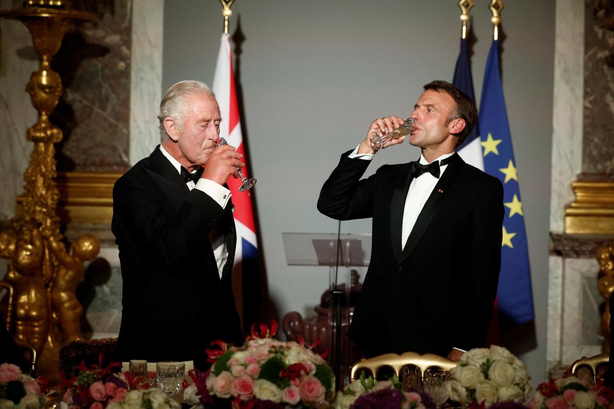 French President Emmanuel Macron (R) and Britain's King Charles III drink after toasting (EPA)