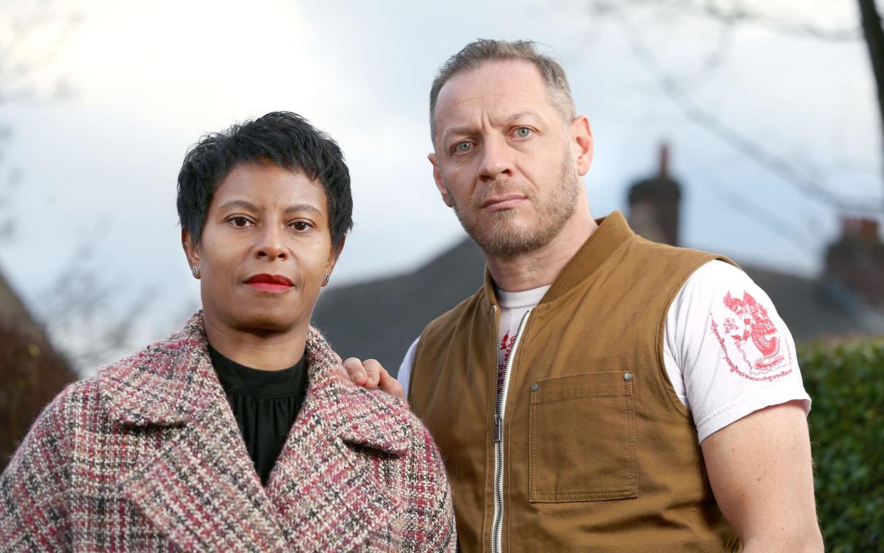 The couple stand together for a portrait, outdoors