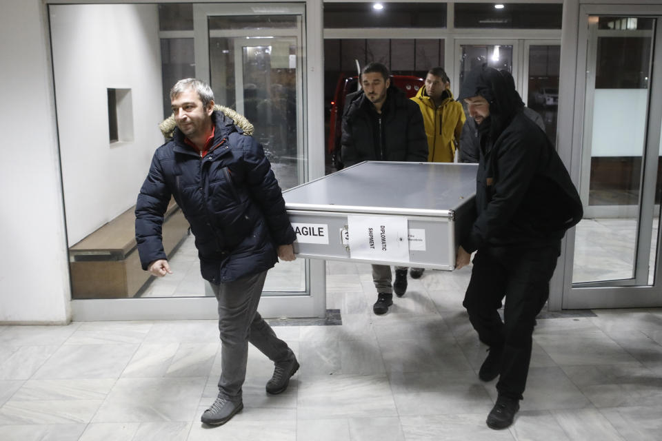 Museum workers carry a box with icons returned from Albania upon the arrival at the National museum in Skopje, North Macedonia, late Friday, Dec. 15, 2023. Albania on Friday returned 20 icons to neighboring North Macedonia that were stolen a decade ago. (AP Photo/Boris Grdanoski)