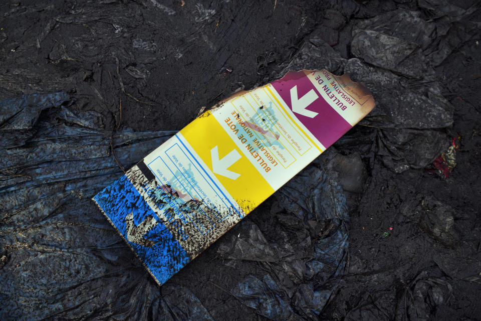 A burned ballot is seen in the mud at the entrance of the Les Anges primary school in Kinshasa, Congo,Sunday Dec. 30, 2018. The voting process was delayed when angry voters burned six voting machines and ballots mid-day, angered by the fact that the registrations lists had not arrived. Replacement machines had to be brought in, and voting started at nightfall, 12 hours late. Forty million voters are registered for a presidential race plagued by years of delay and persistent rumors of lack of preparation. (AP Photo/Jerome Delay)