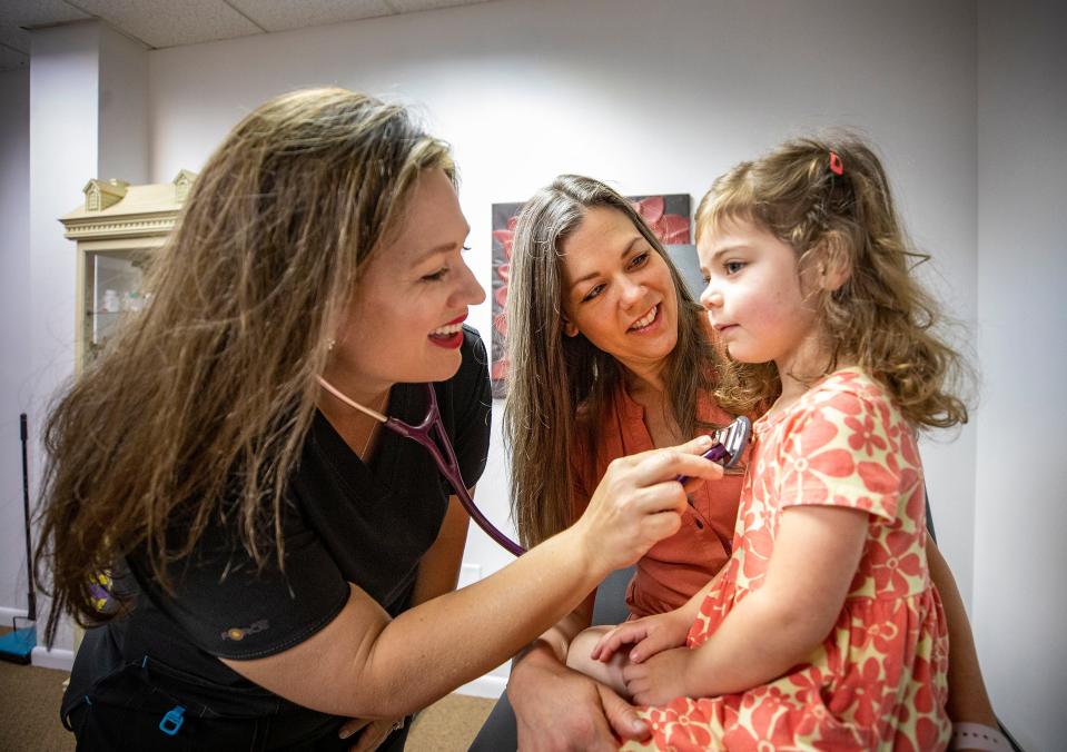  Dr. Alicia Wooldridge , a primary care physician , examines Abigail Brocato and her mom Anna Brocato at her office in Lakeland Fl. Tuesday May 24,  2022. Wooldridge opened a direct primary care clinic in February in Lakeland hoping to spend more time with patients and giving patients a more affordable healthcare option; as she negotiates directly for her patient's tests and treatments and offers some prescription drugs bypassing expensive insurance company plans.ERNST PETERS/ THE LEDGER
