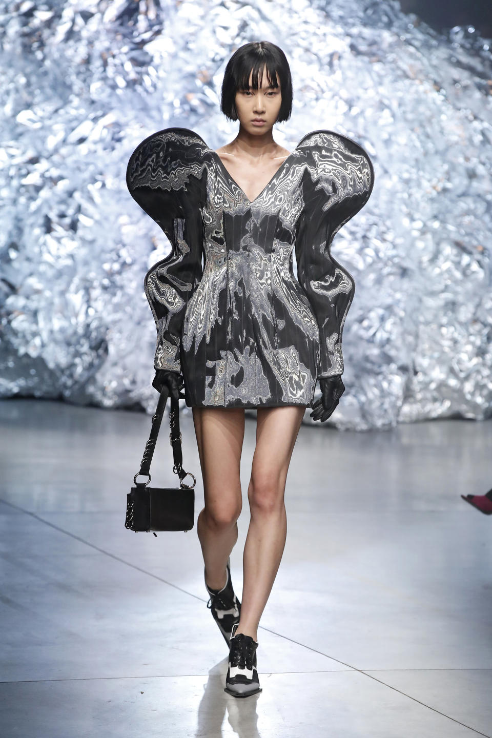 Model on runway in oversized metallic puffed-sleeve dress with matching bag and shoes