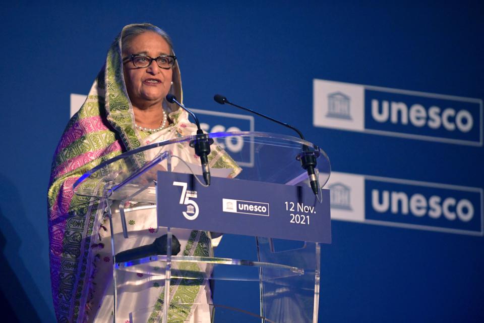 Sheikh Hasina speaks into microphones at a clear podium with a sign reading: 75 UNESCO 12 Nov. 2021.