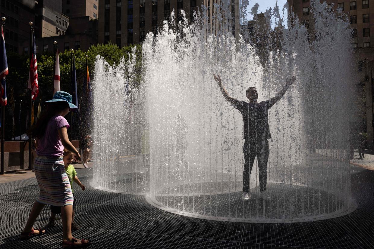 People play in the water-based sculpture of artist Jeppe Hein titled "Changing Spaces" at Rockefeller Center Plaza in New York City on Tuesday, as a heat wave continues throughout Europe and North America.