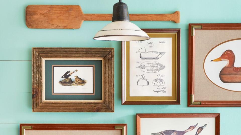 wall with duck prints, decoy paintings, and cross stitch art