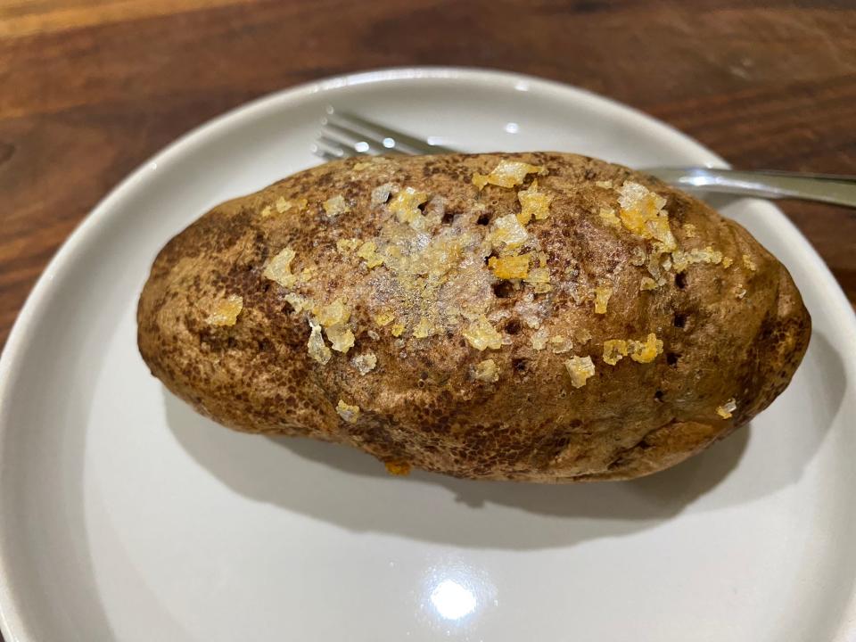 baked potato on a white plate with a fork