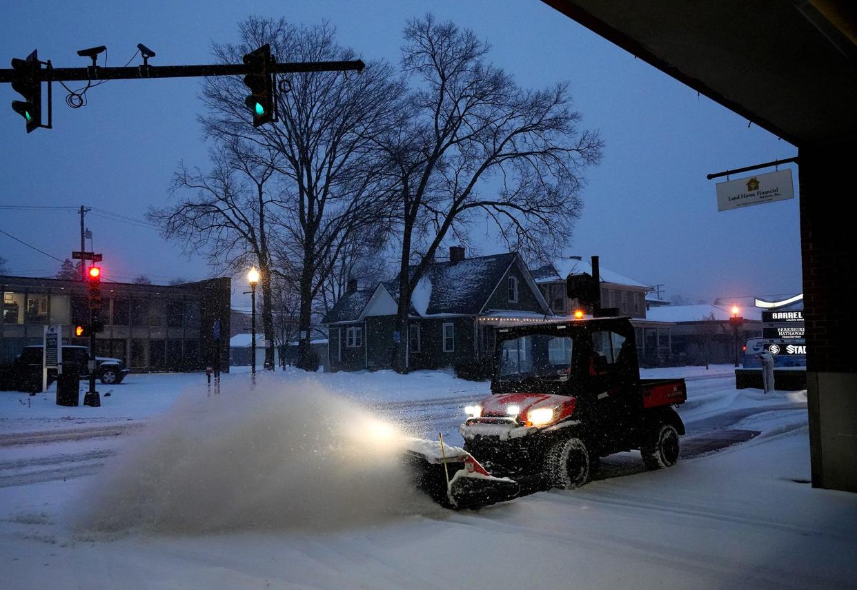 A worker at Creekside. in Gahanna cleans the sidewalk along Mill St. during Winter Storm Landon on Thursday.