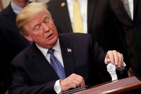 U.S. President Donald Trump holds a space astronaut toy as he participates in a signing ceremony for Space Policy Directive at the White House in Washington D.C., U.S. December 11, 2017. REUTERS/Carlos Barria