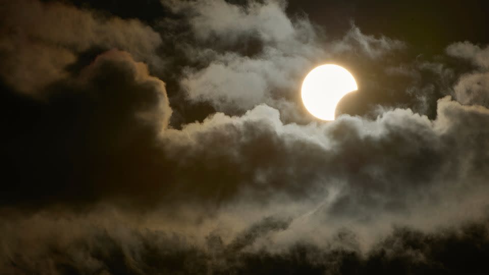 A partial solar eclipse is seen between the clouds from Socorro in Sao Paulo, Brazil on October 14, 2023. - Igor do Vale/Sipa/AP