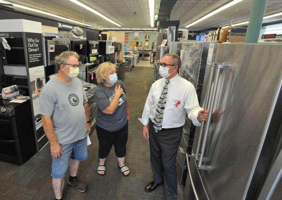 Robert Billings, left, and Karen Crombie, center, both of Weymouth, are assisted in selecting a refrigerator by George Toma, right, owner of George Washington Toma TV & Appliance in Weymouth, during the sales tax holiday on Saturday, Aug. 14, 2021.