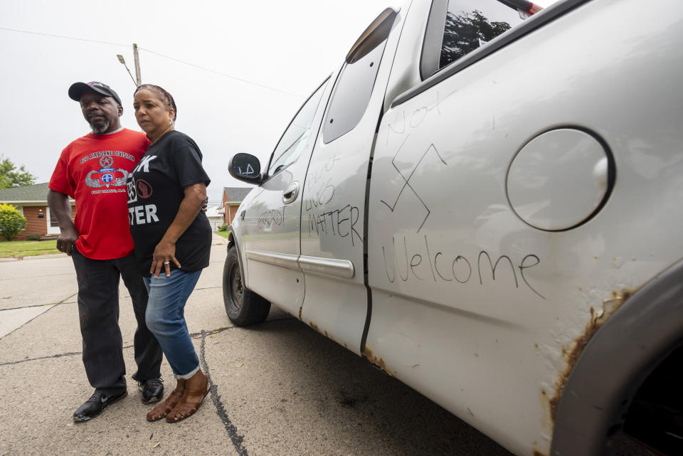 Eddie Hall Jr. and his wife Candace stand in front of threatening graffiti on their truck outside their Warren, Mich., home on Thursday, Sept. 10, 2020. An arrest has been made in connection with vandalism and shots fired into the couple's home. Warren Police Commissioner Bill Dwyer confirmed the arrest Tuesday night, Sept. 29 but didn't elaborate on charges or the person arrested. (David Guralnick/Detroit News via AP)