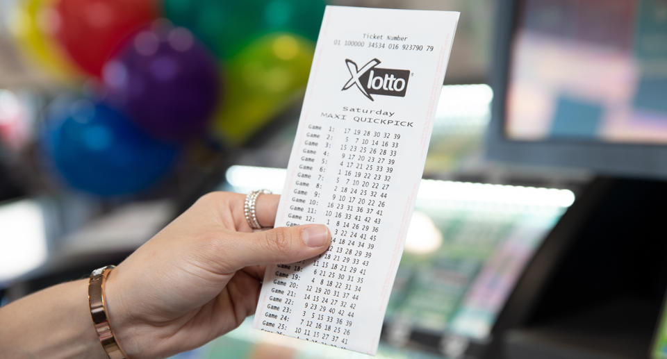 A woman holds a lotto ticket in a newsagency.