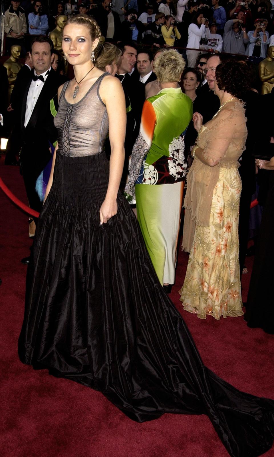 Gwyneth Paltrow poses on the red carpet at the 2002 Oscars in a black and gray gown.