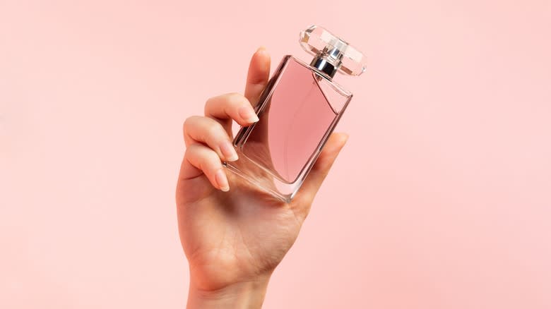 Holding bottle of pink perfume