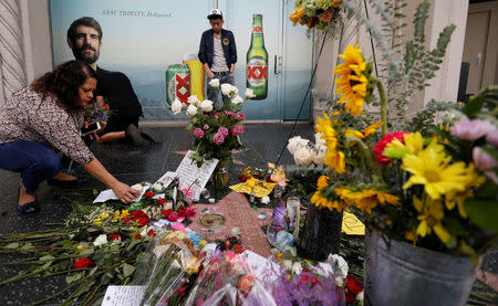 A woman places a flower on the star of Tom Petty and the Heartbreakers which is adorned with other flowers and items, on the Hollywood Walk of Fame in Los Angeles, California, U.S. October 3, 2017. REUTERS/Mario Anzuoni