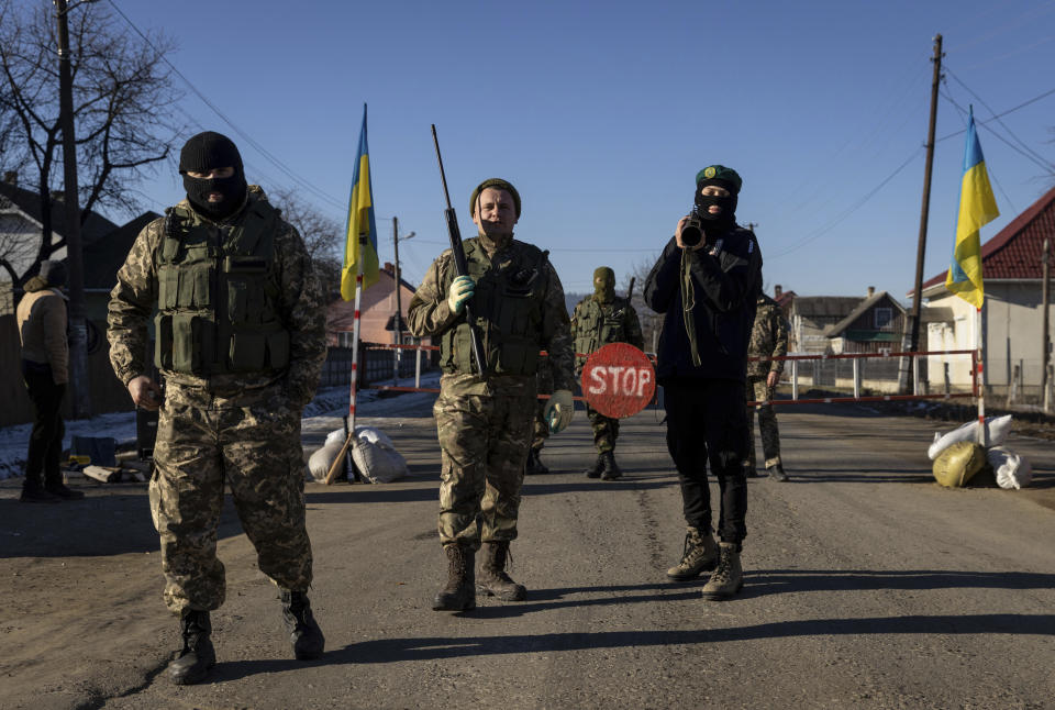 Villagers, dressed as soldiers, guard a check point during Malanka celebrations near the village of Krasnoilsk, Ukraine, Thursday, Jan. 13, 2022. (AP Photo/Ethan Swope)