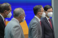 Hong Kong Chief Executive John Lee, right, lines up with his new members of cabinet during a news conference in Hong Kong, Tuesday, July 5, 2022. Lee said Tuesday in his first news conference since taking the reins that he will work towards legislating easing restrictions for travelers, but that it must be balanced with limiting the spread of the coronavirus so as not to overwhelm the healthcare system. (AP Photo/Kin Cheung)