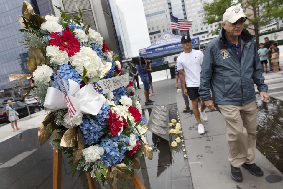 People file past a wreath in memory of Marine Sgt. Johanny Rosario Pichardo, from Lawrence, Mass., after placing a rose at the Massachusetts Fallen Heroes Memorial, Saturday, Aug. 28, 2021, in Boston. The 13 roses are in memory of the U.S. service members killed in a suicide bombing at the airport in Kabul, Afghanistan, including Rosario. (AP Photo/Michael Dwyer)