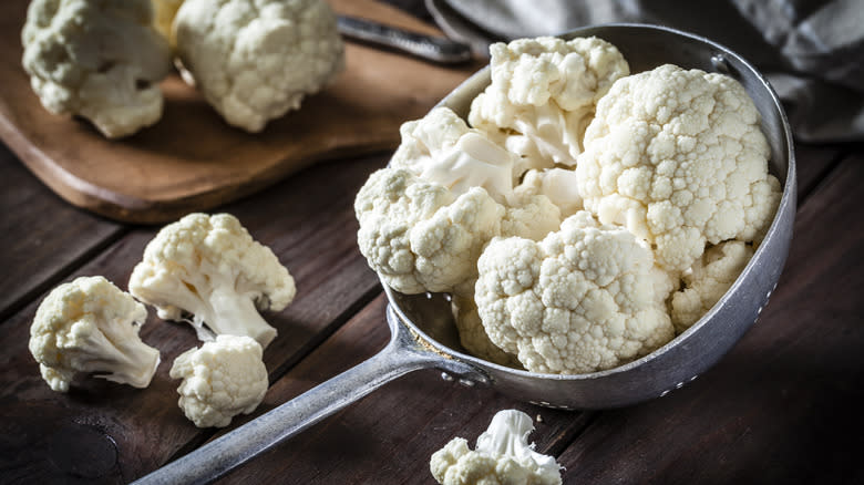 cauliflower in colander on wooden board