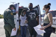 A U.S. Customs and Border Protection agent, left, drops off a migrant couple a member of of a humanitarian group, right, receives them after their release from custody, Friday, Sept. 24, 2021, in Del Rio, Texas. (AP Photo/Julio Cortez)