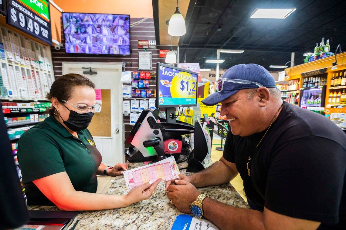 Miguel Gonzalez, right, gets lottery tickets at PriceChoice Supermarket in Miami as employee Yolanda Vindel helps on July 29, 2022.