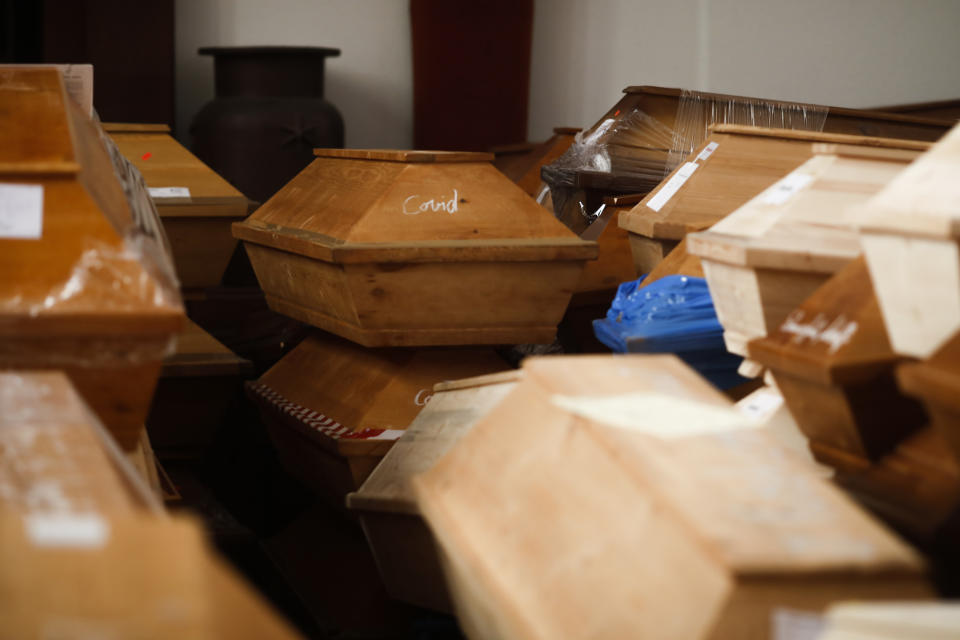 Coffins containing deceased people wait in the worship room of the crematorium in Meissen, Germany, before cremation on Monday, Jan. 11, 2021. For those who died with the coronavirus, the coffins are marked with the word "COVID" as a warning. (AP Photo/Markus Schreiber)